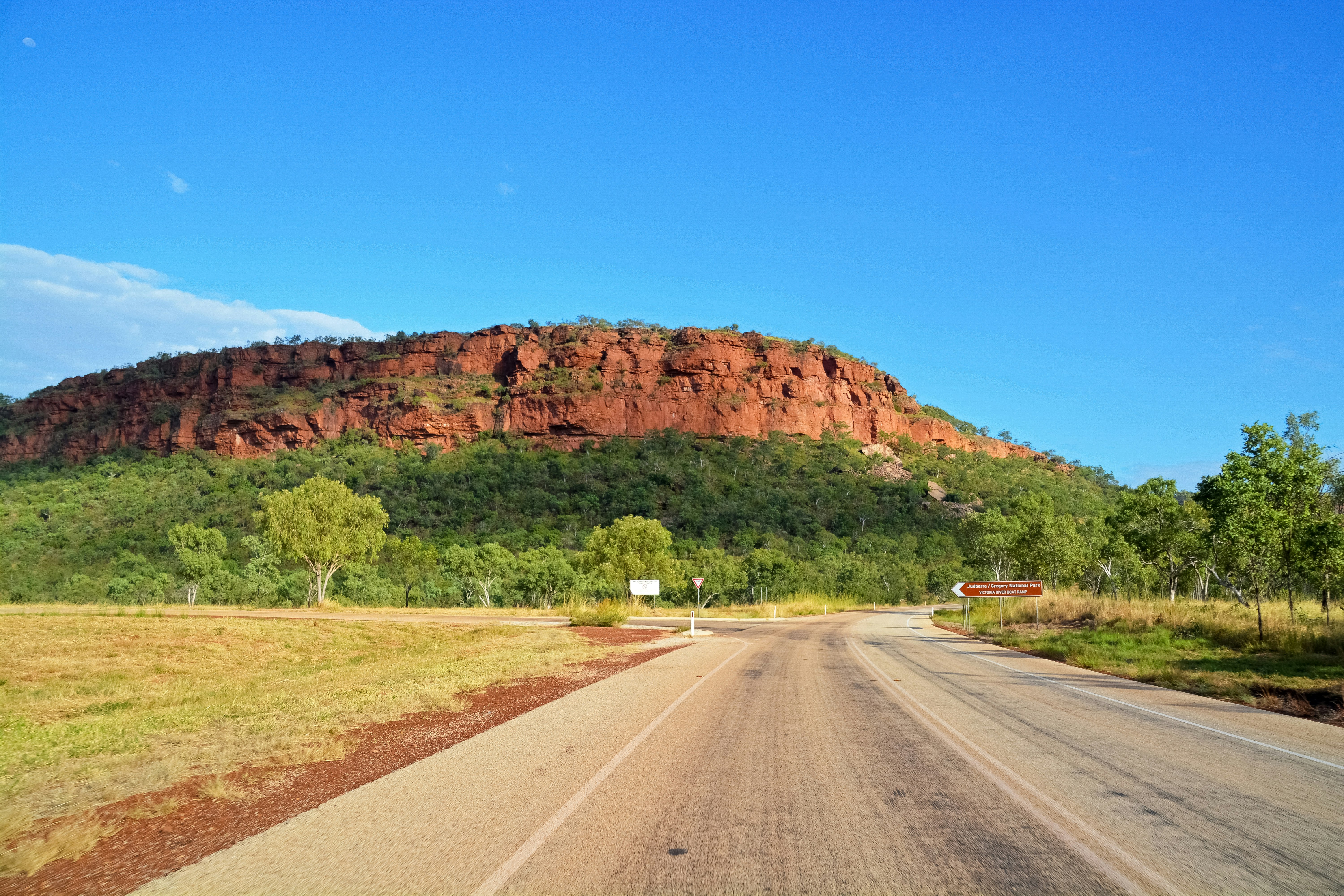 gray asphalt road near brown mountain under blue sky during daytime